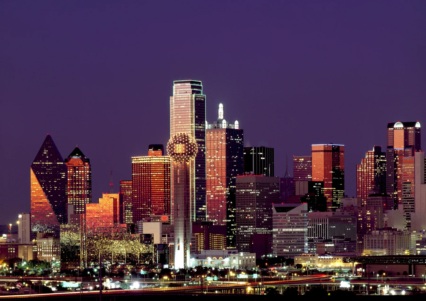 The Dallas skyline glowing at dusk, with Reunion Tower in front of downtown